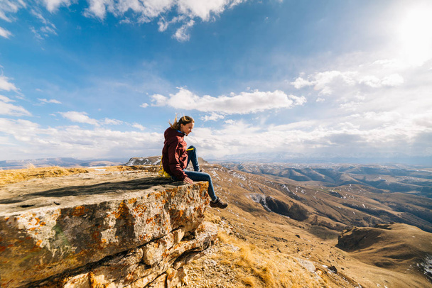 turystyczna kobieta siedzi na tle gór w słoneczny dzień - Zdjęcie, obraz