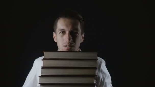 Junger Mann hält einen Stapel Bücher in den Händen - Filmmaterial, Video