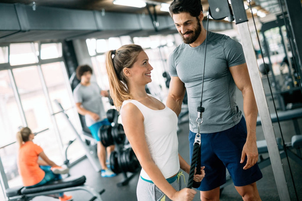 Personal trainer assisting woman lose weight in gym - Фото, зображення