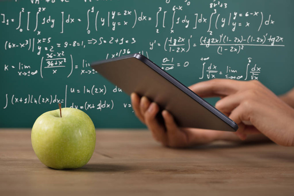 Primer plano de la mano de un estudiante usando tableta digital con manzana verde en el escritorio
 - Foto, imagen