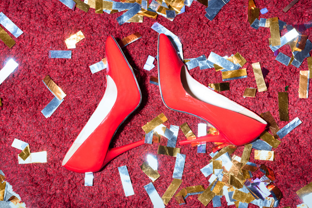top view of pair of red feminine shoes on floor with confetti - Фото, зображення