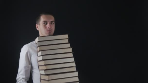 Young man takes up a pile of books. Businessman with books in hands. - Imágenes, Vídeo