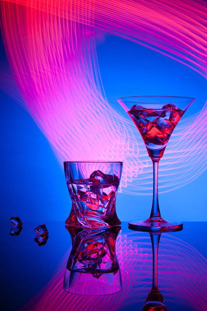 Δυο ποτήρια μια κοκτέιλ Martini ουίσκι πάγο, όμορφα εφέ φωτός μπλε φόντο. - Φωτογραφία, εικόνα