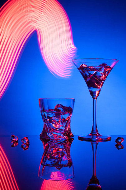 Два келихи коктейль Martini віскі лід, на синьому фоні красивих світлових ефектів
. - Фото, зображення