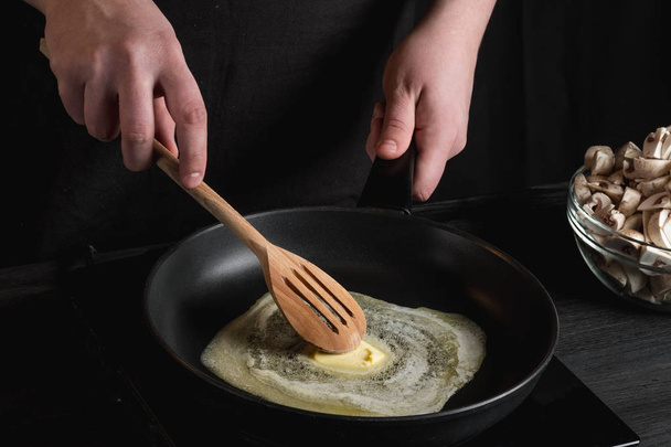 Kokki ruoanlaitto voita pannulla käyttäen puinen astiasto
  - Valokuva, kuva