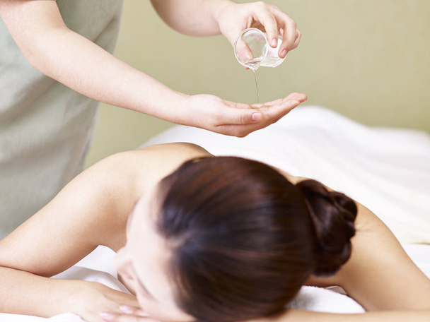 masseur performing oil massage on young asian woman - Fotoğraf, Görsel