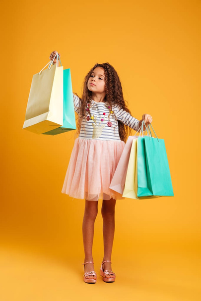 Thinking girl child holding shopping bags. - 写真・画像