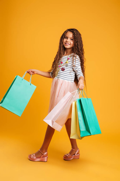 Cheerful girl child holding shopping bags. - 写真・画像