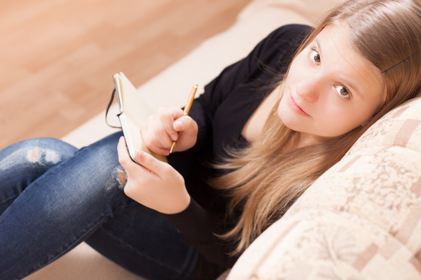 adolescente feliz escribiendo para el diario sentado en el sofá de la sala - Fotoğraf, Görsel