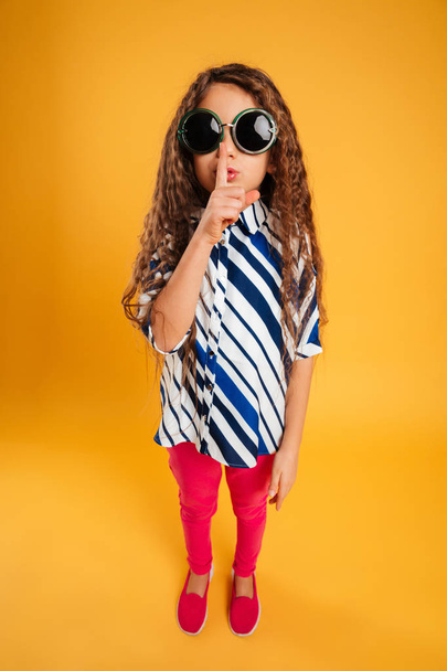 Little girl child wearing sunglasses showing silence gesture. - Фото, зображення