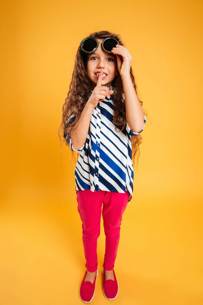 Little girl child wearing sunglasses showing silence gesture. - Фото, зображення