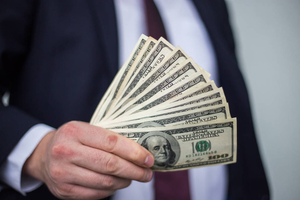 Άνθρωπος των επιχειρήσεων εμφανίζει μια εξάπλωση των μετρητά πάνω από ένα λευκό vintage ΒΑ - Φωτογραφία, εικόνα