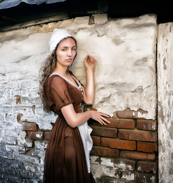 pensive young woman in a rustic dress standing near old brick wall in old house feel lonely. Cinderella style - Φωτογραφία, εικόνα