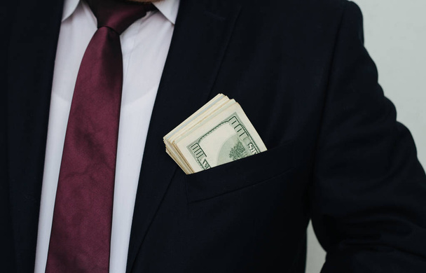 Een zakenman toont een som geld, zet het in zijn zak van kleur - Foto, afbeelding