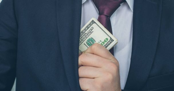 A businessman shows a sum of cash, puts it in his pocket of suit - Fotó, kép