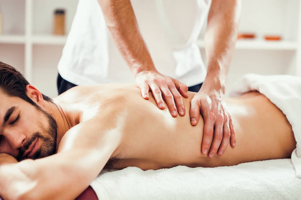 Young man is enjoying massage on spa treatment.  - Foto, Imagen