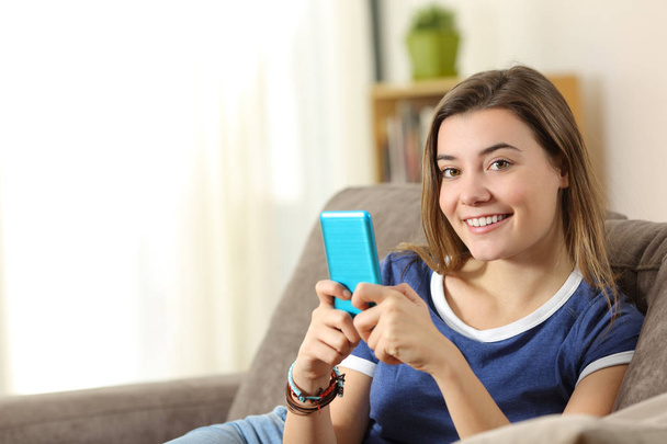 Счастливый подросток держит смартфон, глядя на тебя
 - Фото, изображение