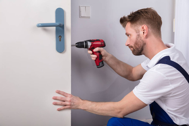 Young Carpenter Install Door Lock With Wireless Screwdriver - Photo, image