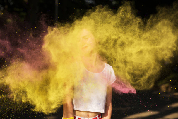 Adorable brunette woman having fun in a cloud of yellow and pink - Φωτογραφία, εικόνα