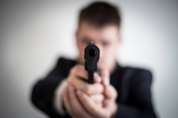 Ένας κλέφτης σε ένα κοστούμι με ένα πυροβόλο όπλο που απευθύνεται σε ένα άτομο παίρνει μετρητά, hundr - Φωτογραφία, εικόνα
