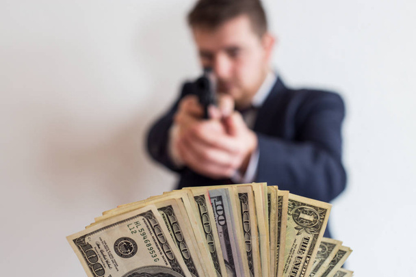 Een dief in een pak met een geweer gericht op een man neemt geld, hundr - Foto, afbeelding