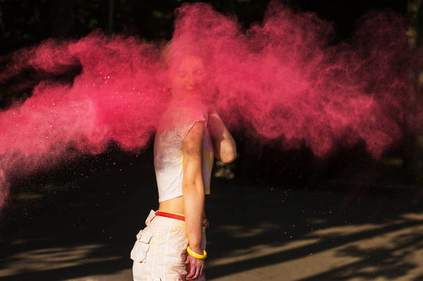 Attractive young woman playing with pink dry paint Holi explodin - Foto, Imagem
