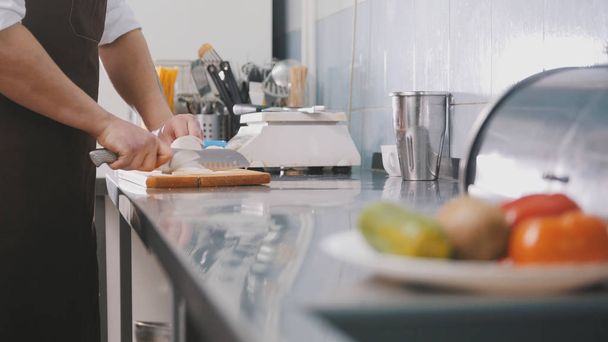 Männerkoch bereitet Salat in Großküche zu - schneidet die Zwiebel - Foto, Bild