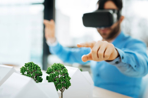 Pleasant architect in VR headset pointing at tree models - Fotografie, Obrázek