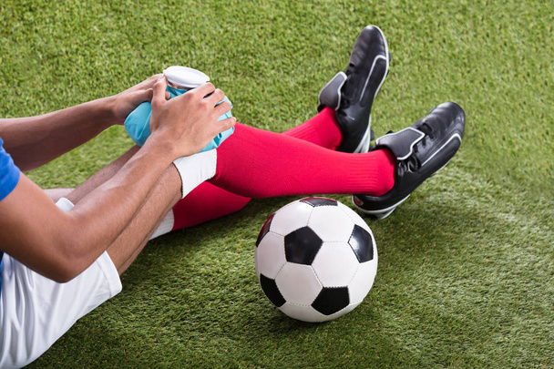 Close-up Of An Injured Male Soccer Player Applying Ice Pack On Knee - Foto, Imagem