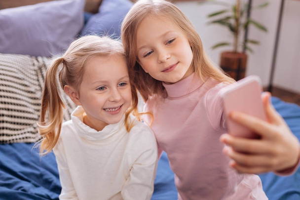 Cheerful blond sisters taking pictures on their phone - Photo, Image