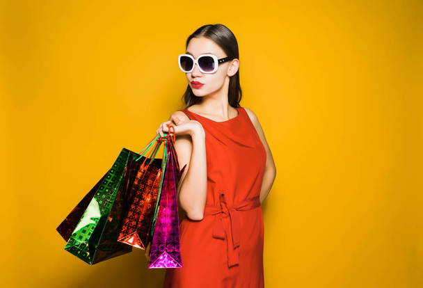 woman in a beautiful red dress keeps shopping bags - 写真・画像