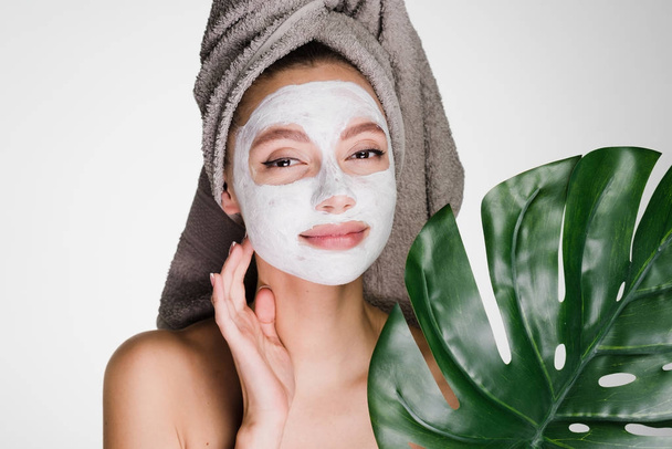 a woman with a towel on her head applied a cleansing mask on her face - Valokuva, kuva