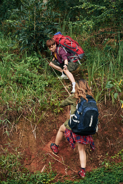 asiático hombre ayudar mujer a subir en colina con cuerda
 - Foto, Imagen