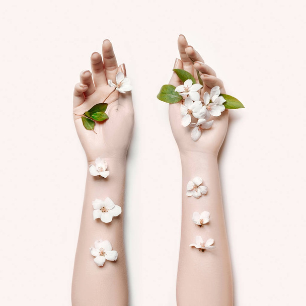 Fashion art hand woman in summer time and flowers on her hand with bright contrasting makeup. Creative beauty photo hand girls sitting at table on contrasting background with colored shadows. Skincare - Valokuva, kuva
