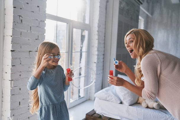 Mother and daughter blowing soap bubbles and laughing - Foto, immagini