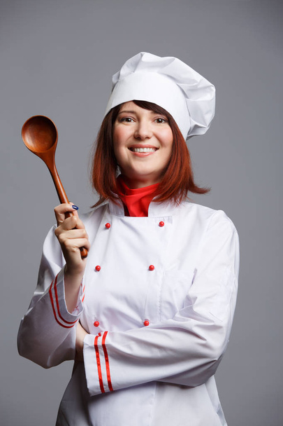 Image of cook girl in white robe and cap with wooden spoon - Foto, immagini