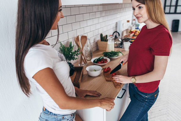 Freundinnen in der Küche bereiten gemeinsam Salat zu. - Foto, Bild