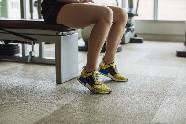 Legs of unrecognisable woman sitting at gym. - Foto, Bild
