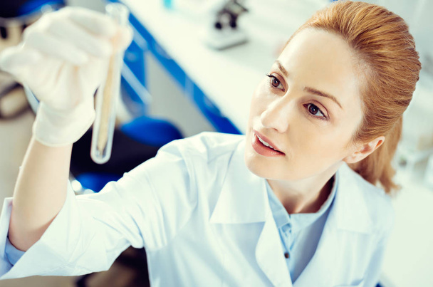 Amazed mature lady analyzing test tube with sample - Фото, изображение