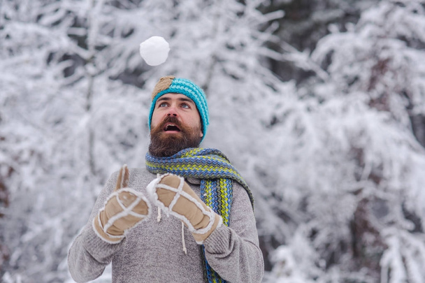 Bearded hipster play with snowball in snowy forest - Фото, зображення