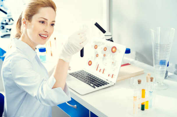 Adult woman analyzing test tube while working in lab - Foto, afbeelding