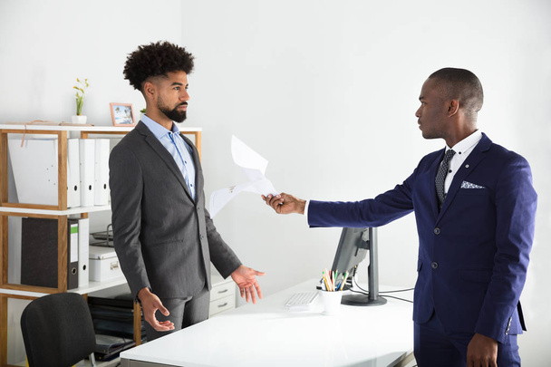 Dissatisfied African Young Boss Giving Document To Employee At Workplace - Фото, зображення
