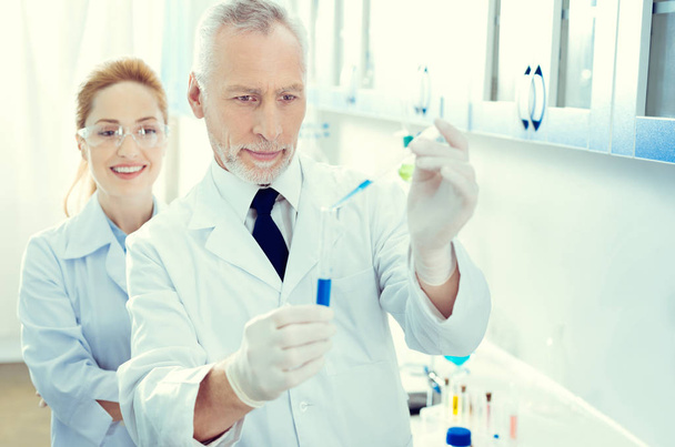 Cheerful researches conducting chemical experiment - Foto, Bild