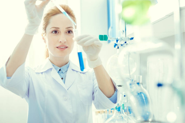 Female researcher mixing chemical liquids in lab - 写真・画像