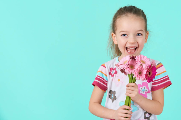 Adorable little girl with cheeky smile and face expression holding bouquet of pink gerbera daisies. Happy Mother's Day, Women's day, Father's day or Birthday background. - Photo, Image