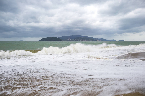 шторм з великими хвилями на узбережжі з горами на фоні
 - Фото, зображення