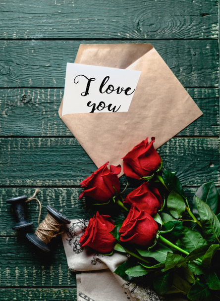 top view of red roses and envelope with I love you valentine card on wooden background - Photo, Image