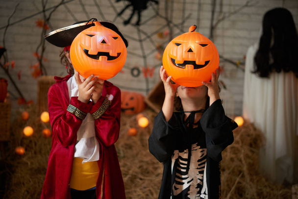 Дети в костюмах показывают страшные тыквенные фонари на Хэллоуин
 - Фото, изображение