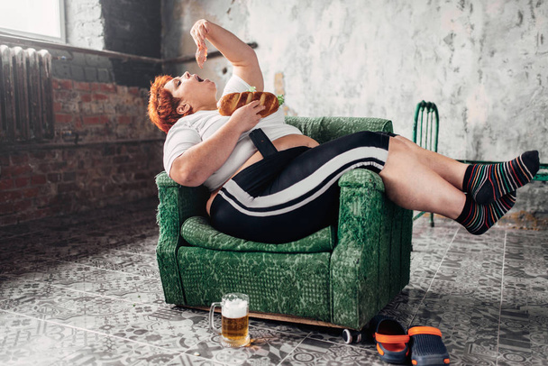 lihava nainen istuu nojatuoli ja syö voileipä, epäterveellinen elämäntapa ja lihavuus käsite
 - Valokuva, kuva