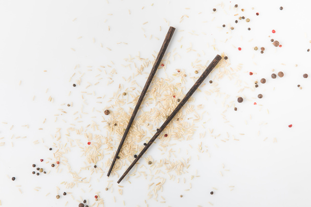 top view of raw rice and spices spilled on white surface with chopsticks - Фото, зображення